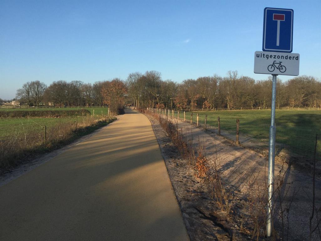 nieuw zandkleurigasfalt met heggetje en wandelpad