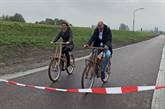 Twee fietsters op houten fiets rijden door rood lint